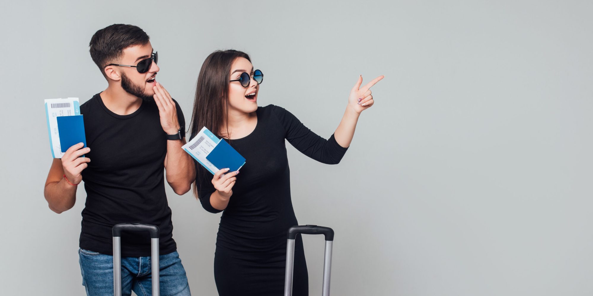 Smiling young happy couple with suitcases and ticket around isolated on white background. Copy space. Place for some text.